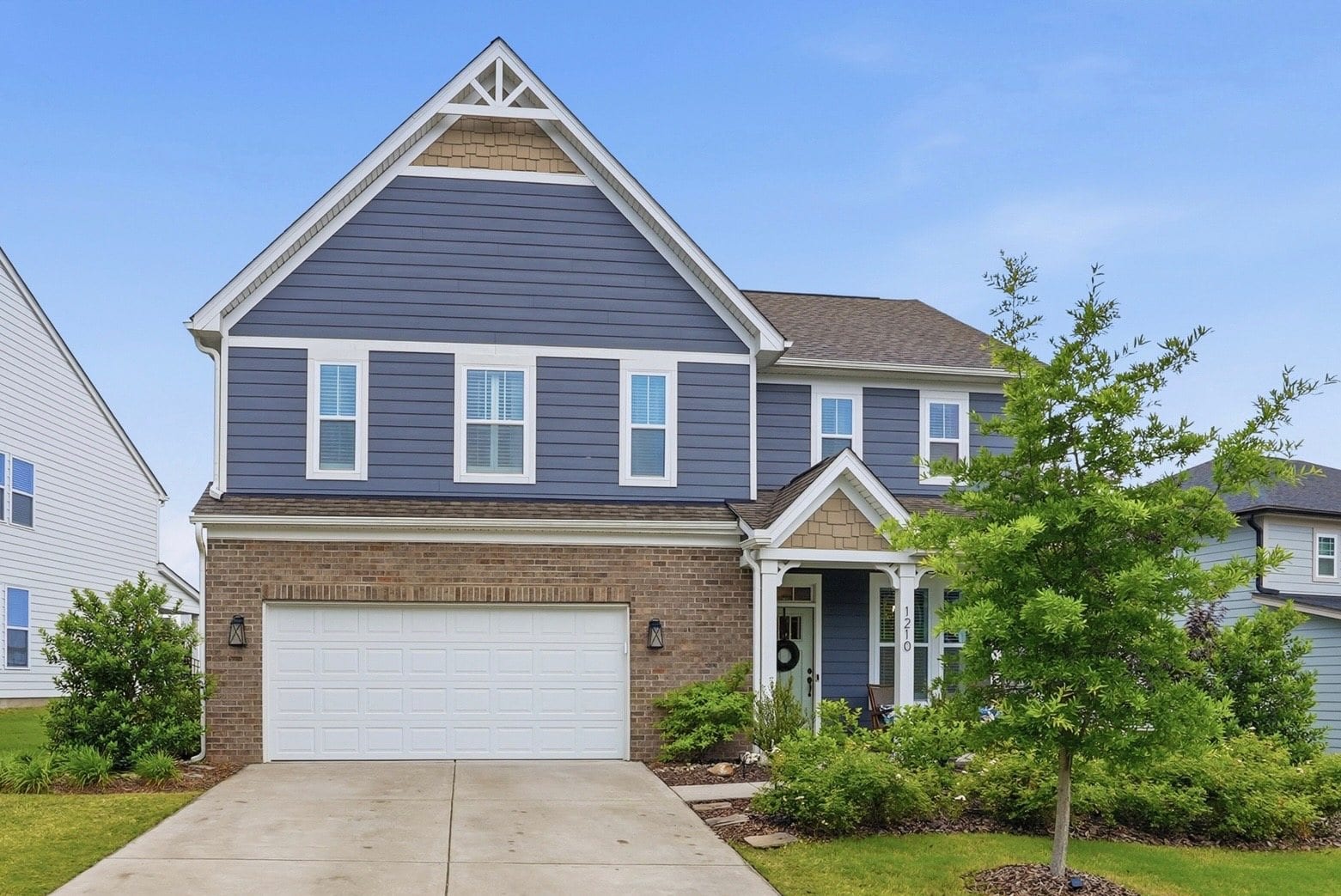 Front elevation of 1210 Therns Ferry Drive — a navy two-story home with a brick base and covered porch
