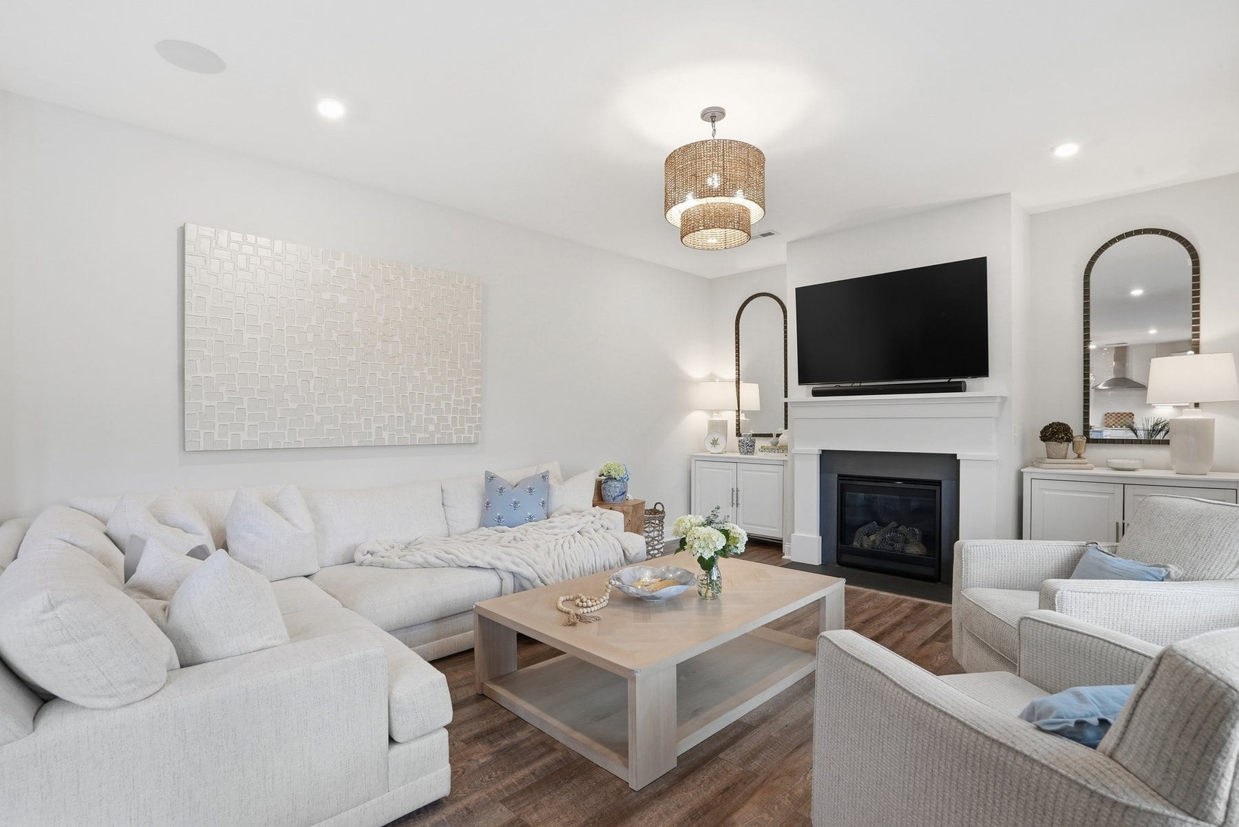 Living room with a fireplace, arched mirror and a sectional beneath a woven pendant