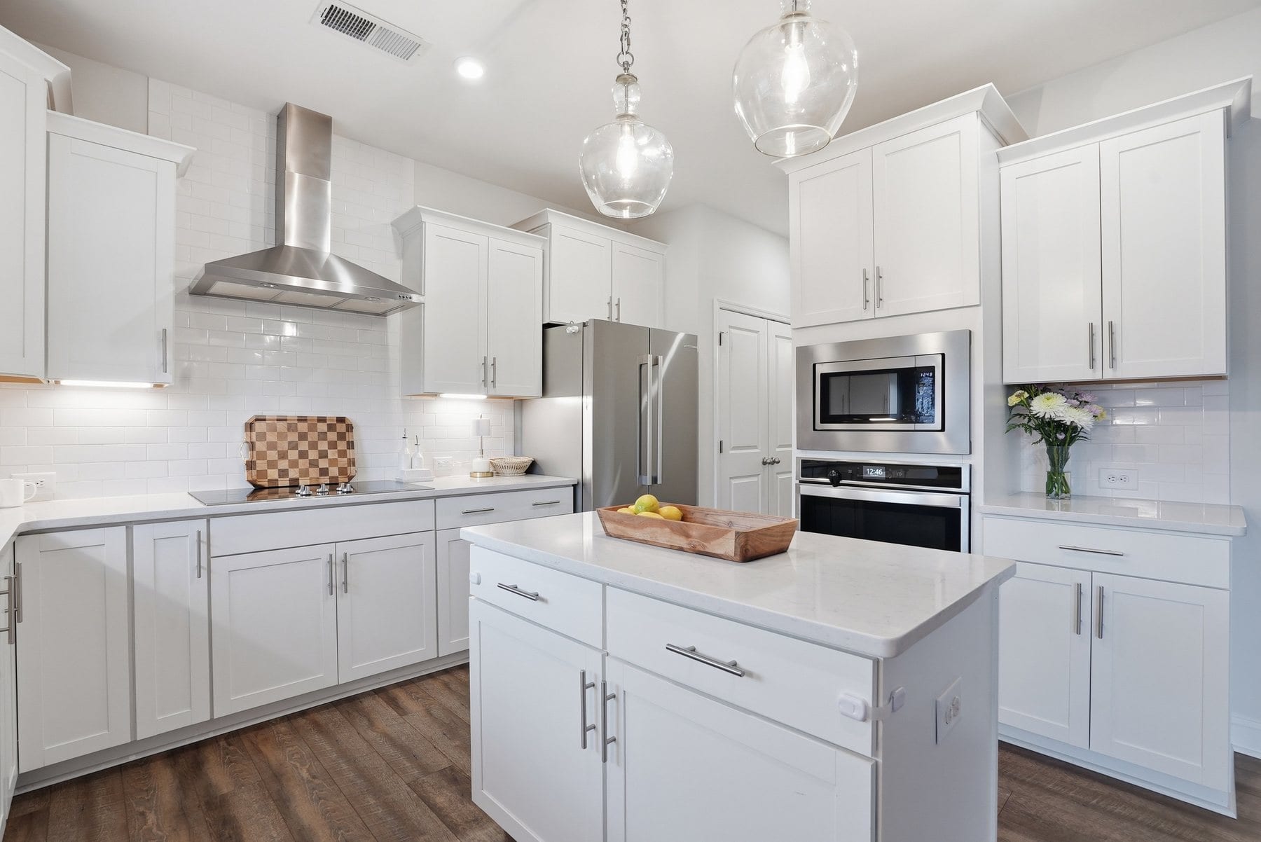 Kitchen with white cabinetry, a stainless hood and quartz counters