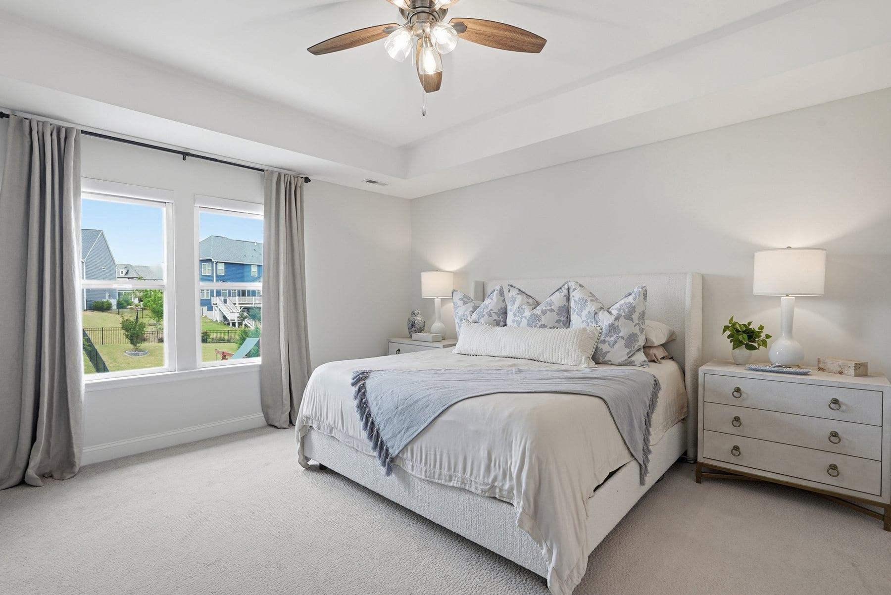 Bedroom with a tray ceiling, ceiling fan and windows to the yard